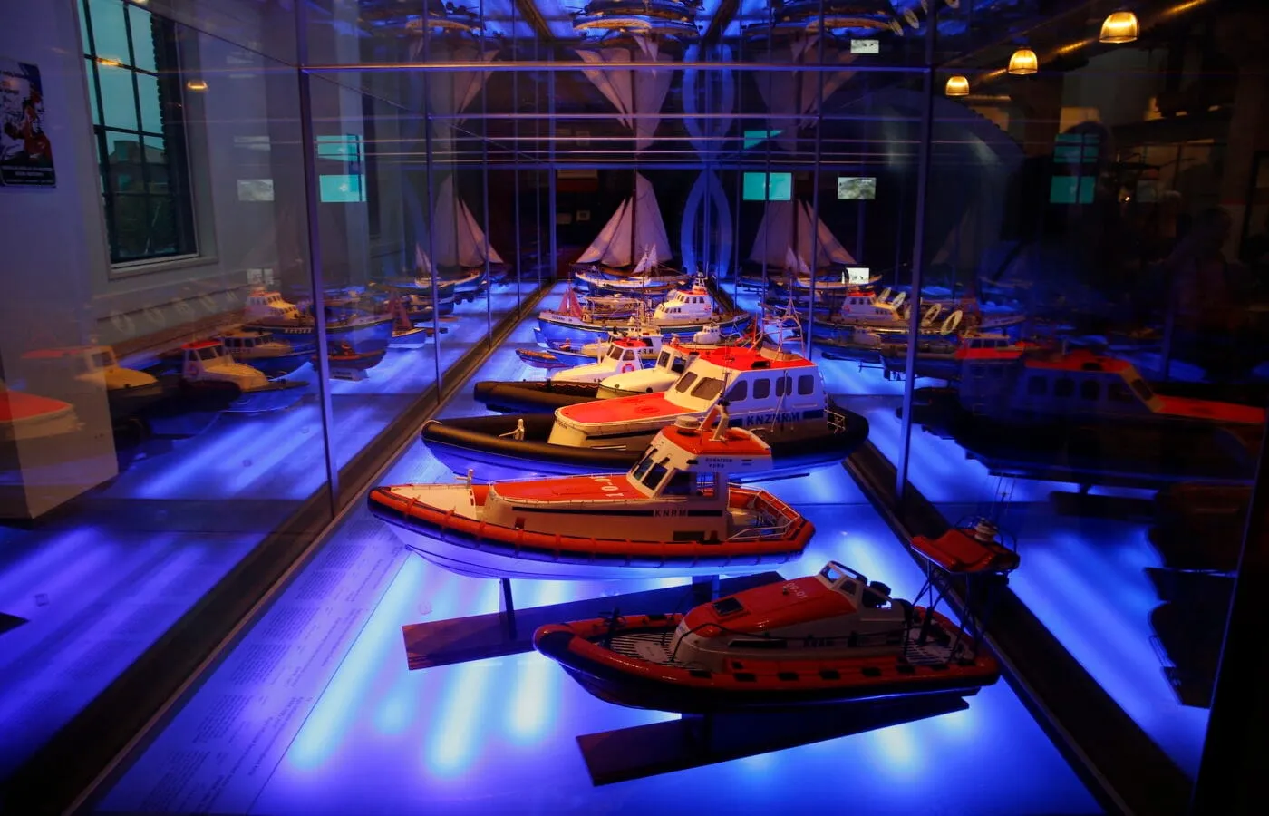 Scale models of lifeboats on display under blue light at the National Lifeboat Museum