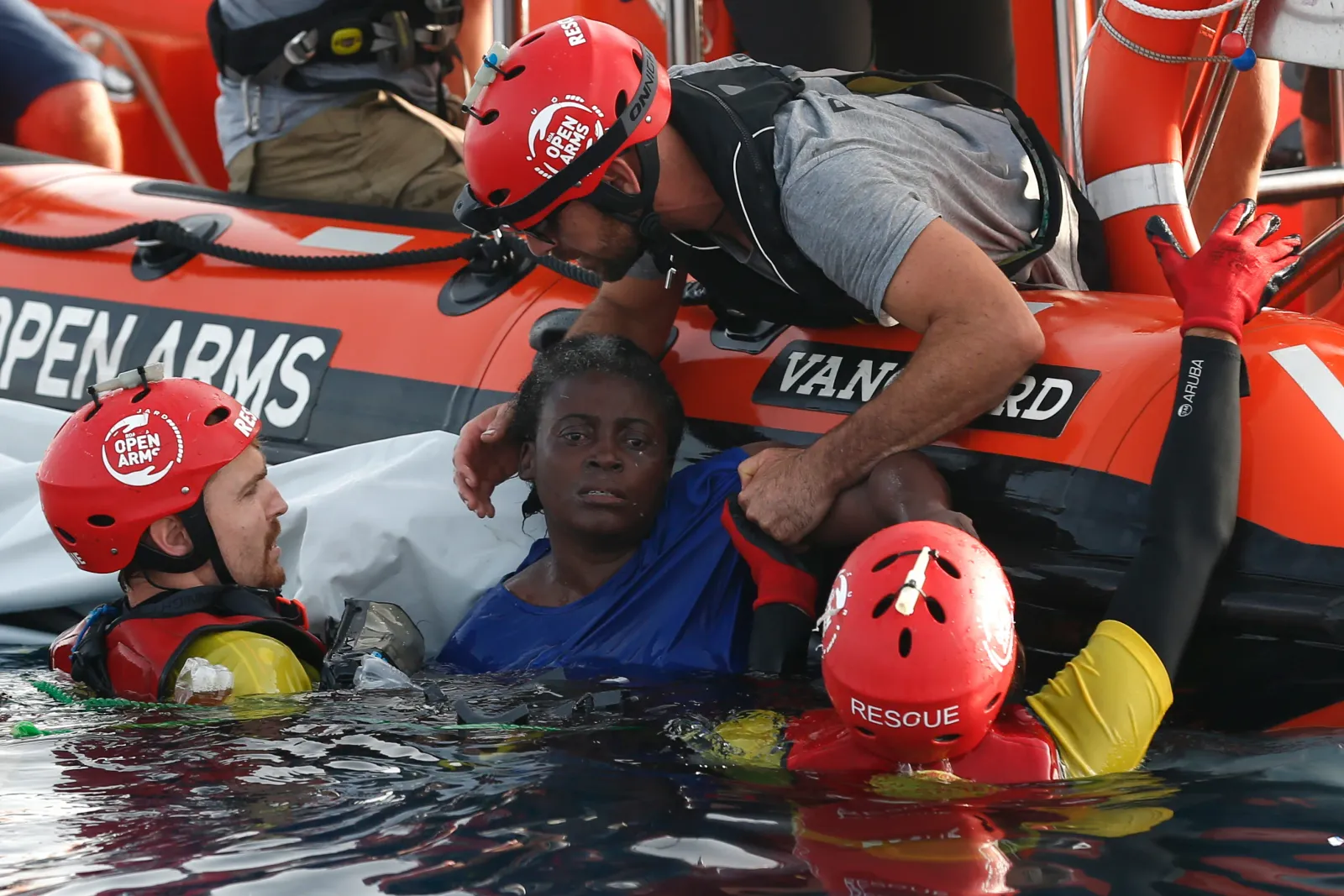 Open Arms rescue crew helping a woman from the water alongside their rescue boat
