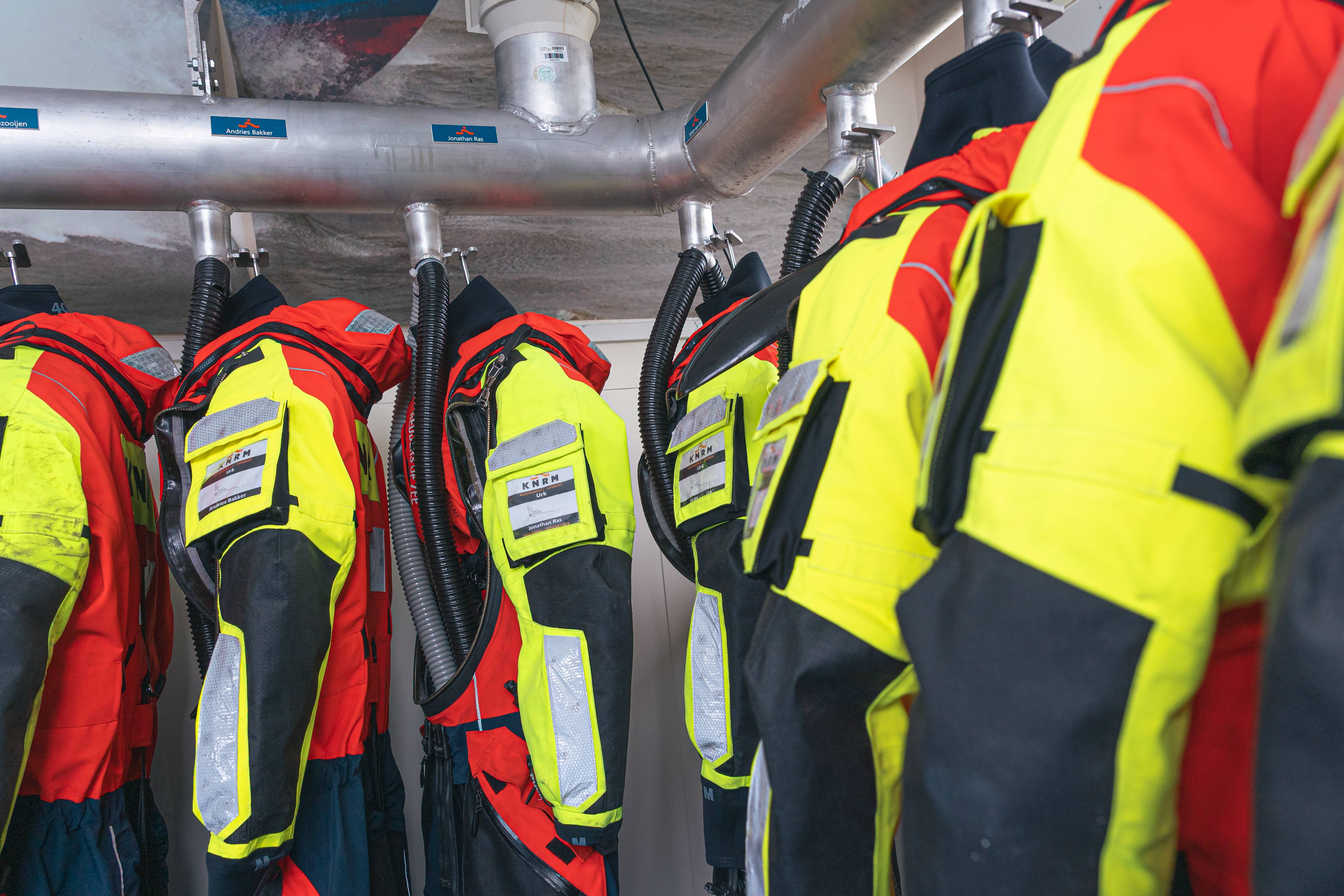 Personalised KNRM survival suits hanging in the boathouse at Urk